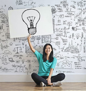 Ideas To Reveal Your Zone Of Genius - Photo of a woman holding a light bulb sign.